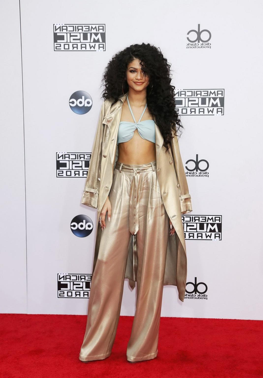 16P Zendaya Coleman wearing hot blue bra under a wide open gold coat at 2014 America