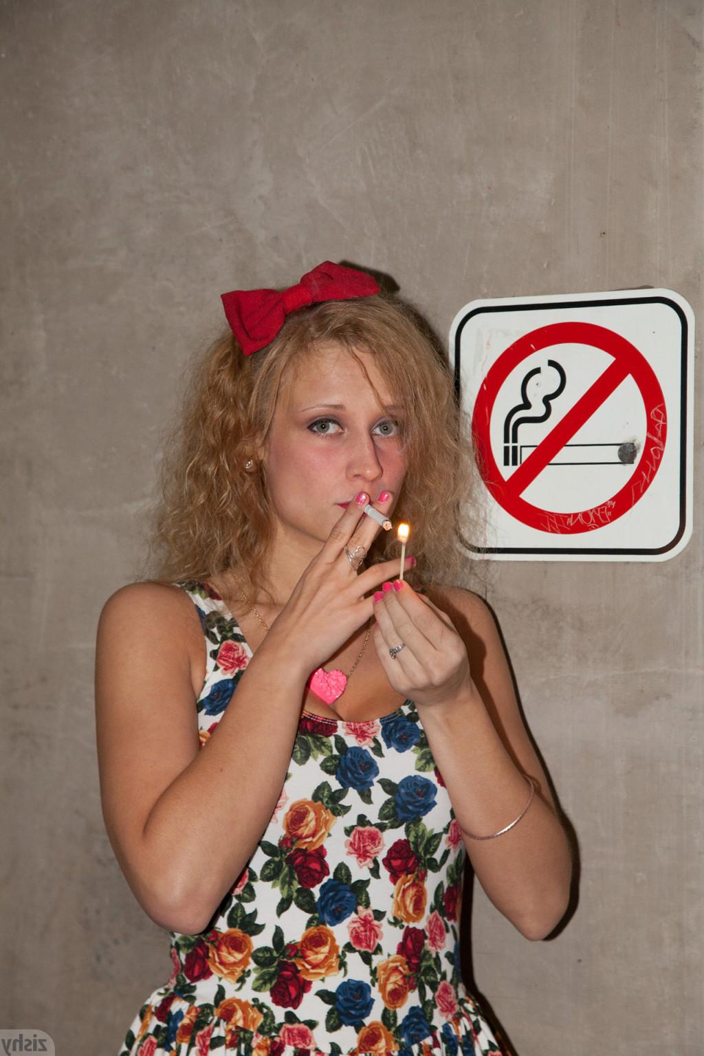 12P Rebel girl with curly hair smoking under a no smoking sign