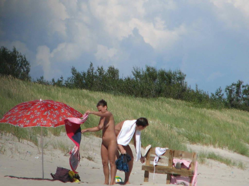 15P Long haired hottie lays around nude at the beach