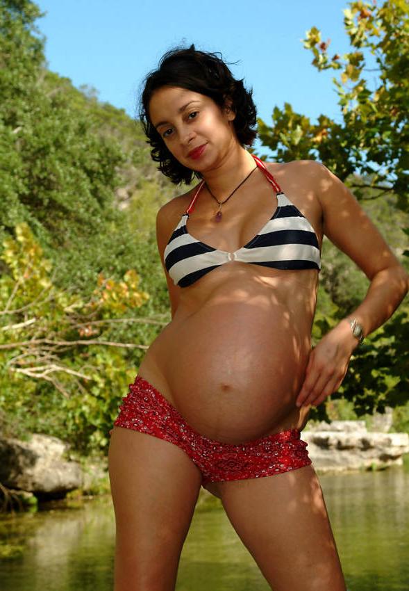 15P Pregnant curly girl posing by water
