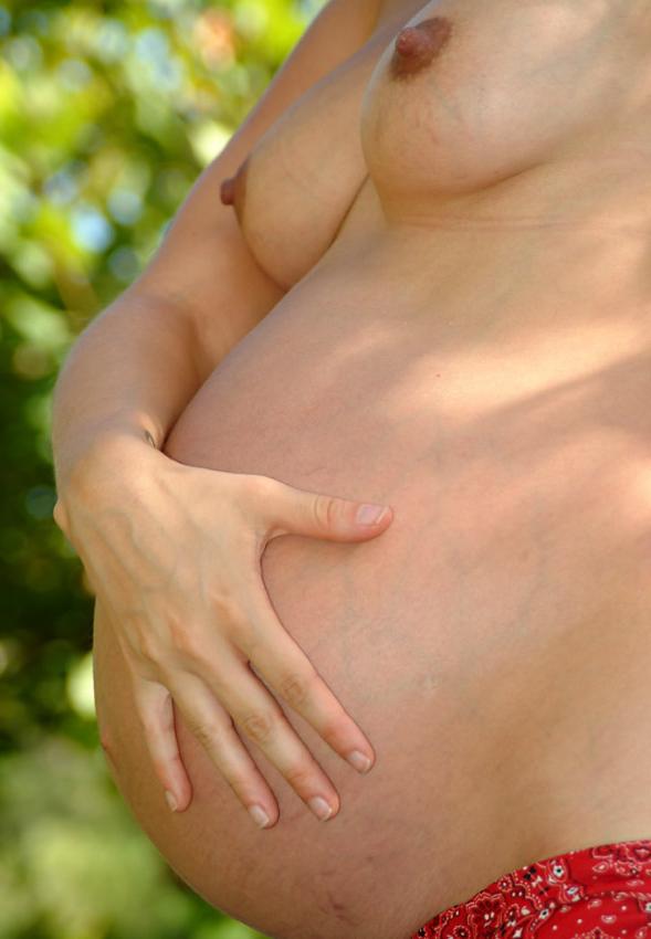 15P Pregnant curly girl posing by water
