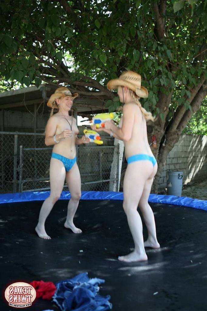 15P Twin teen sisters play with water pistols and jump on trampoline