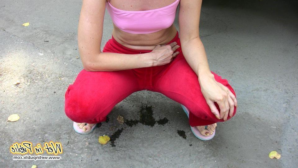 16P Cutie hides behind a truck to pee right through her red sporty pants