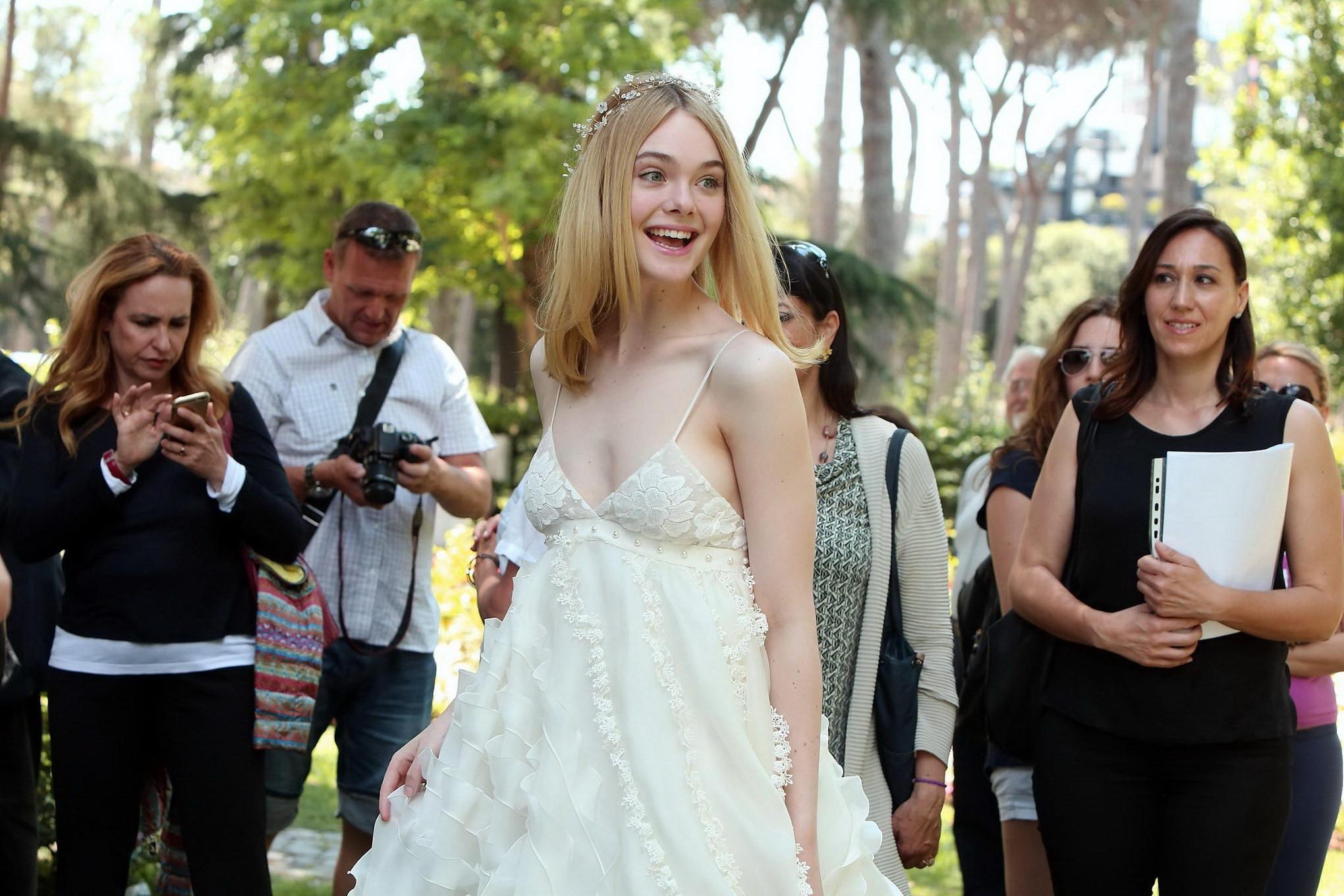 15P Elle Fanning cleavy and leggy in white lace dress