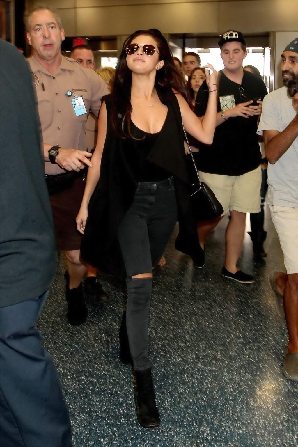 16P Selena Gomez braless showing big cleavage in a black top and jeans at the airpor