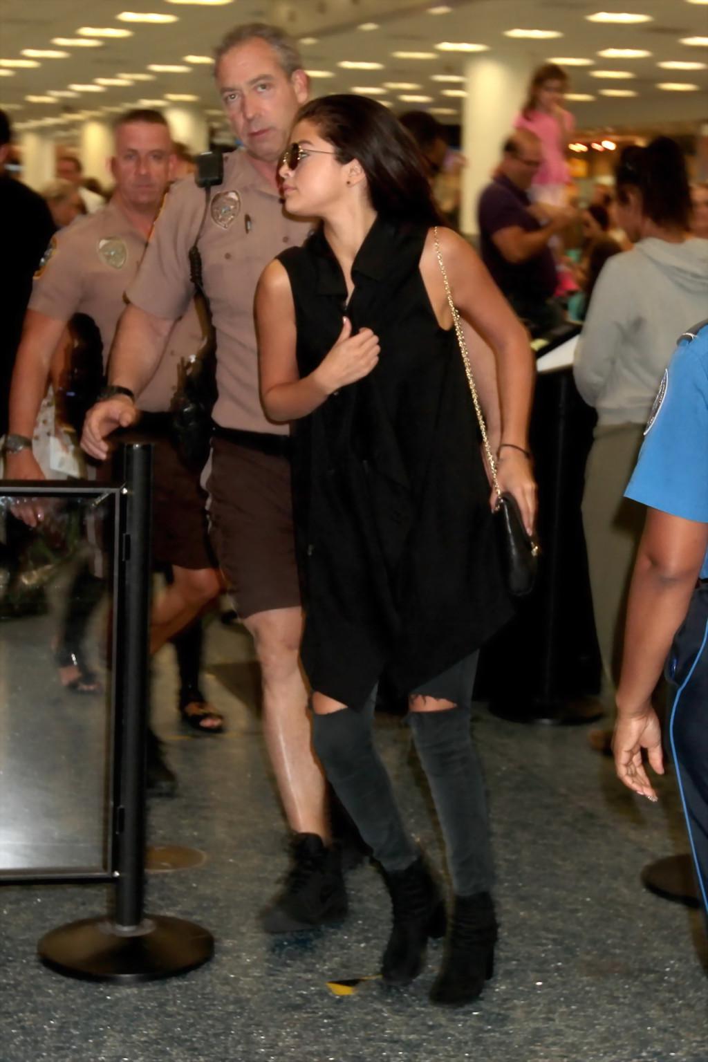 16P Selena Gomez braless showing big cleavage in a black top and jeans at the airpor