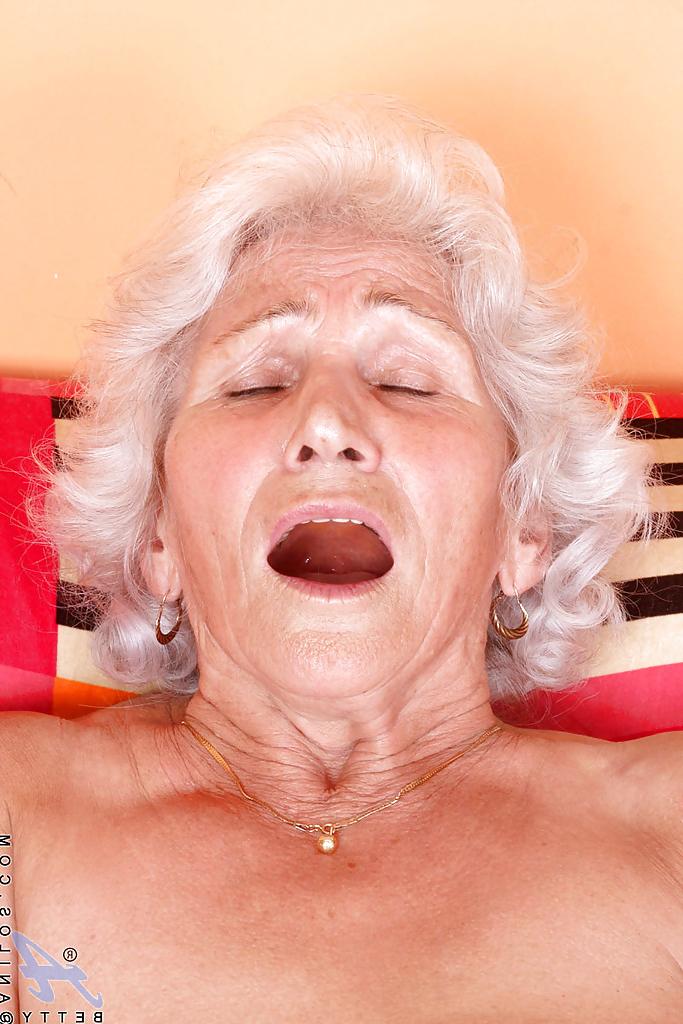 16P Blonde Oma in glänzenden weißen Strümpfen entblößt ihre Brüste und masturbiert