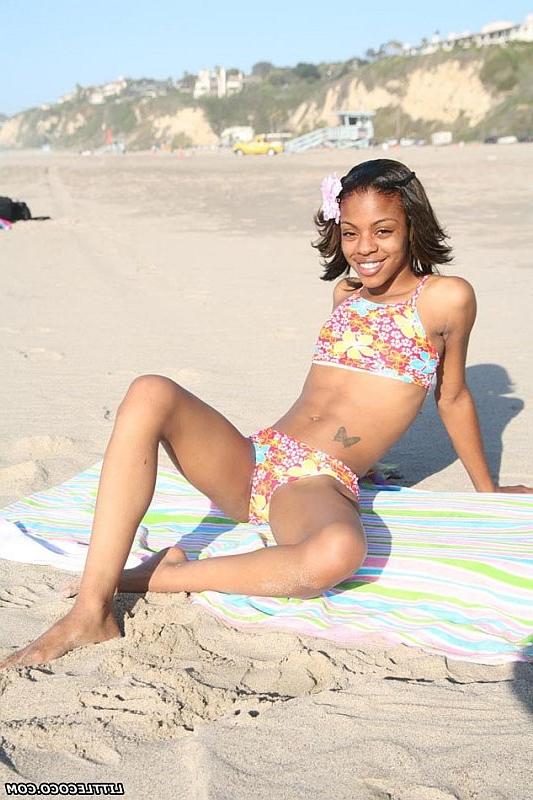 16P Petite ebony chick getting naked and posing on the beach