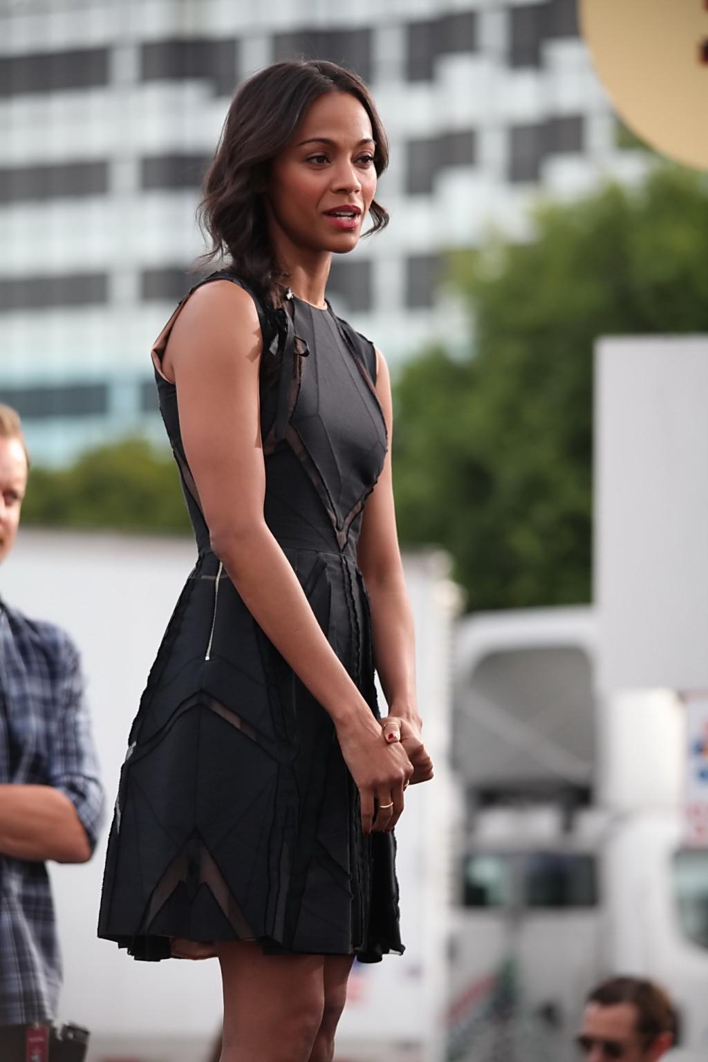 16P Zoe Saldana wearing black partially see-through mini dress on 'Extra' set at the