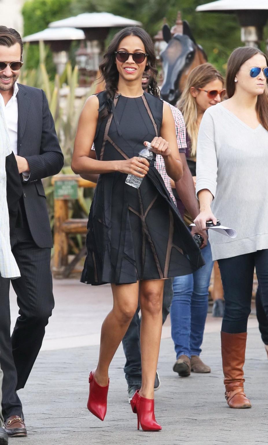 16P Zoe Saldana wearing black partially see-through mini dress on 'Extra' set at the