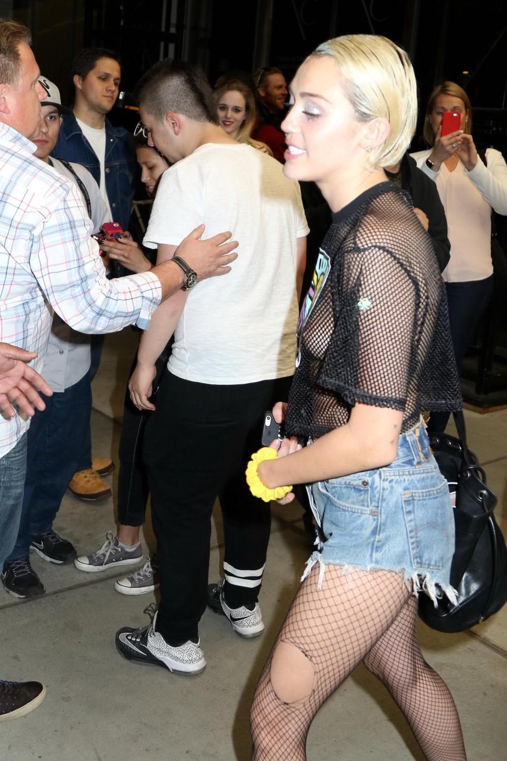 16P Miley Cyrus shows off her boobs wearing a mesh Tshirt out in NYC