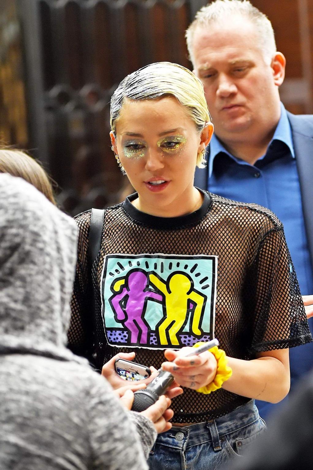 16P Miley Cyrus shows off her boobs wearing a mesh Tshirt out in NYC