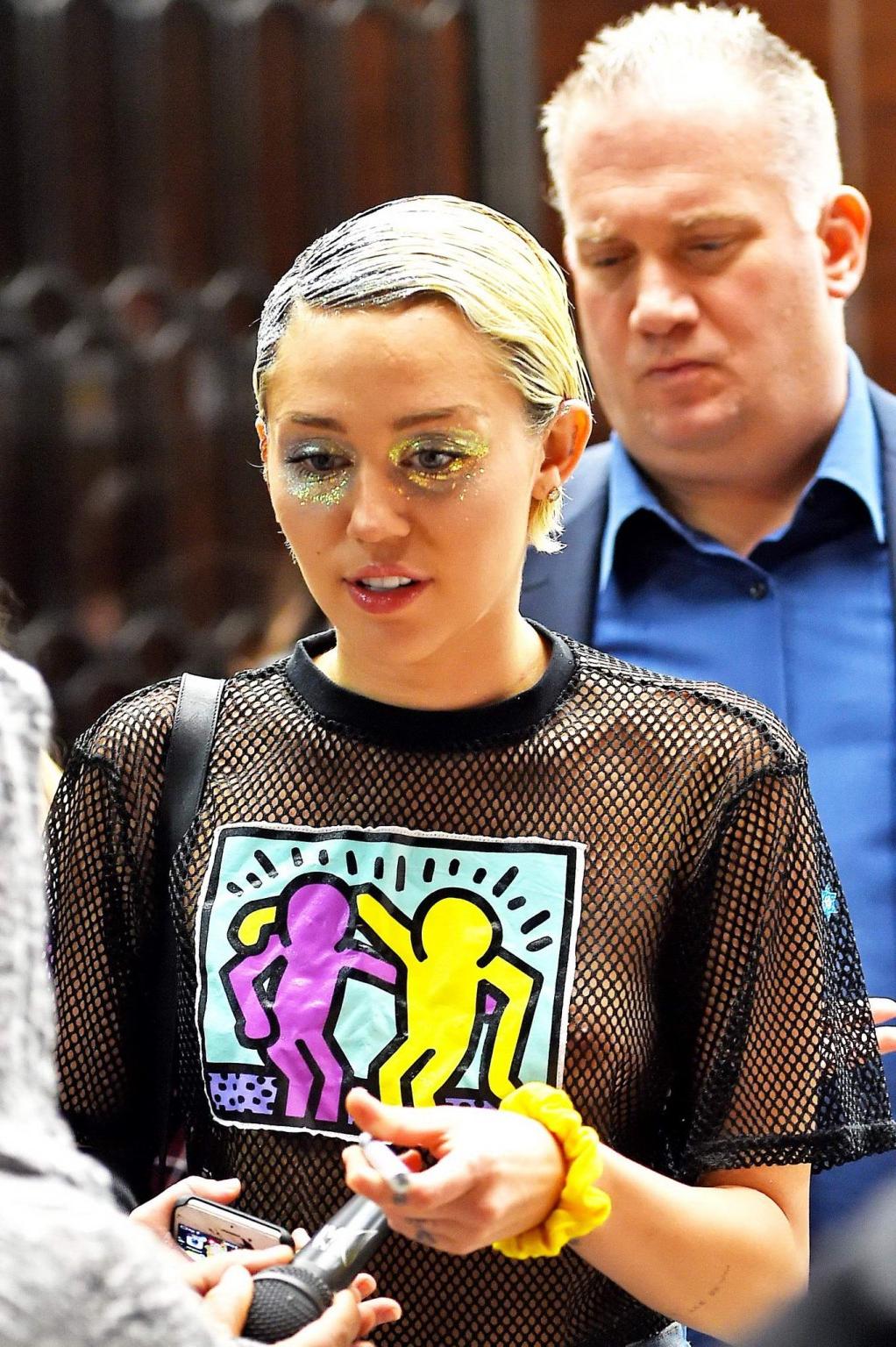 16P Miley Cyrus shows off her boobs wearing a mesh Tshirt out in NYC