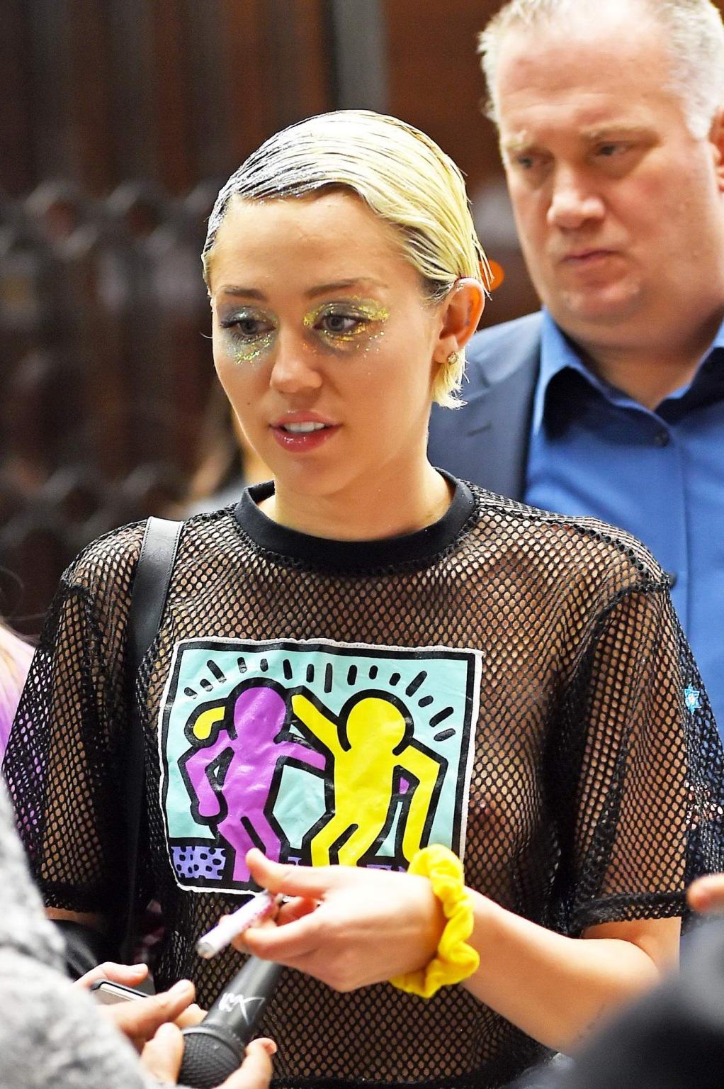16P Miley Cyrus shows off her boobs wearing a mesh Tshirt out in NYC