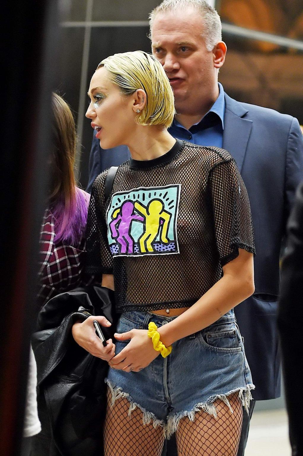 16P Miley Cyrus shows off her boobs wearing a mesh Tshirt out in NYC