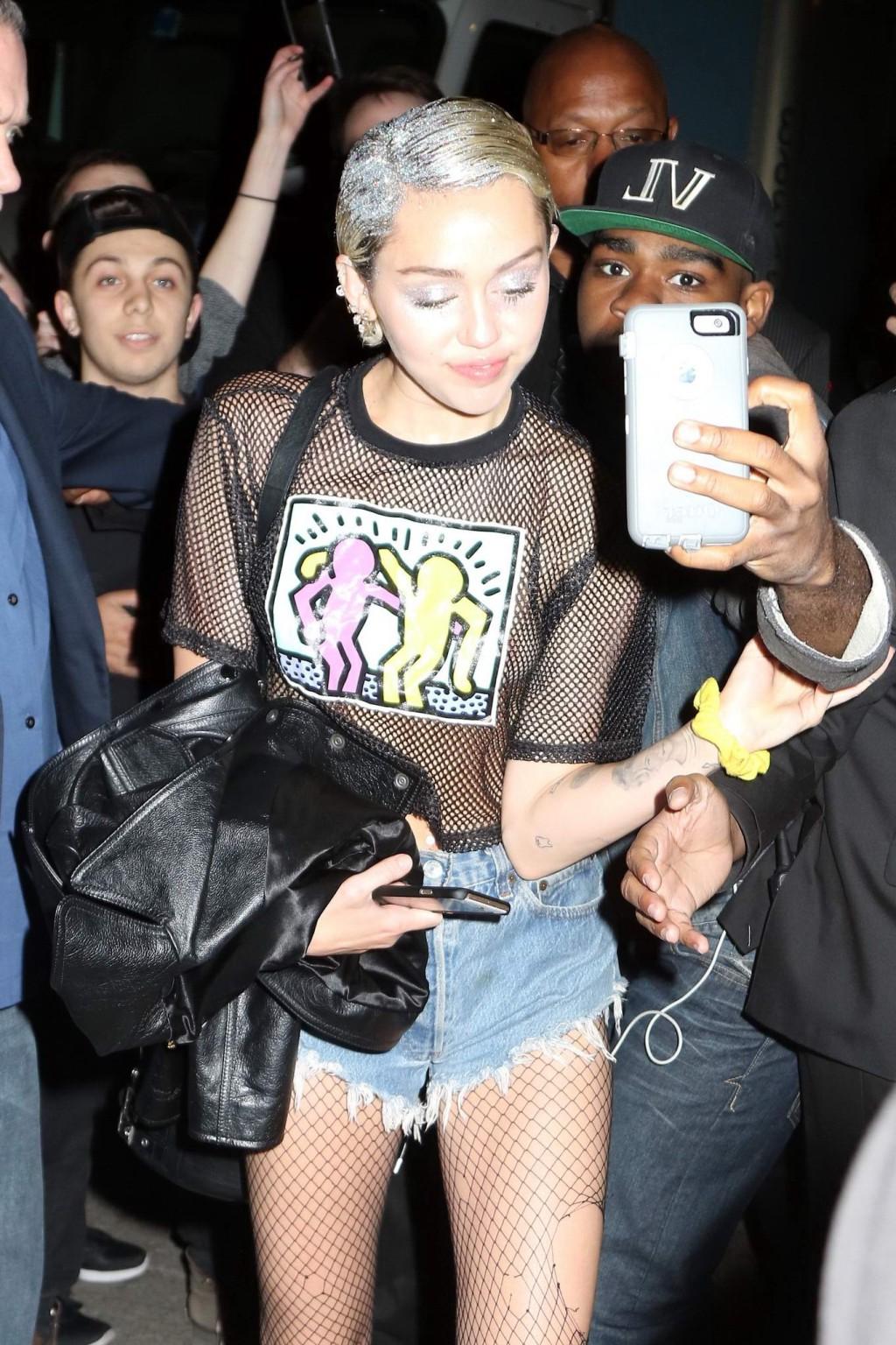 16P Miley Cyrus shows off her boobs wearing a mesh Tshirt out in NYC