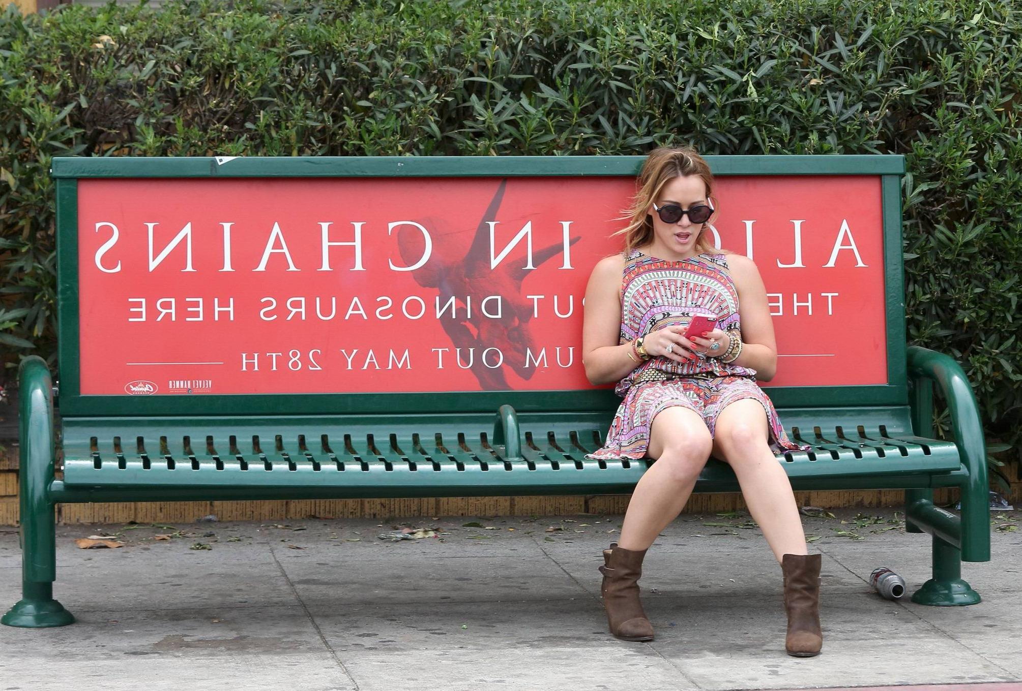 16P Hilary Duff upskirt wearing colorful mini dress while pretending to wait for a b