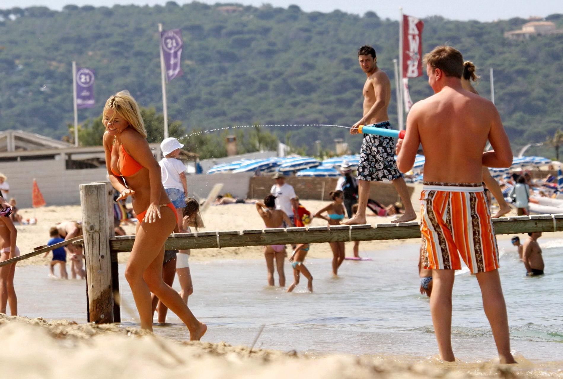 15P Busty Geri Halliwell showing pokies in skimpy orange bikini at Club 55 beach in 