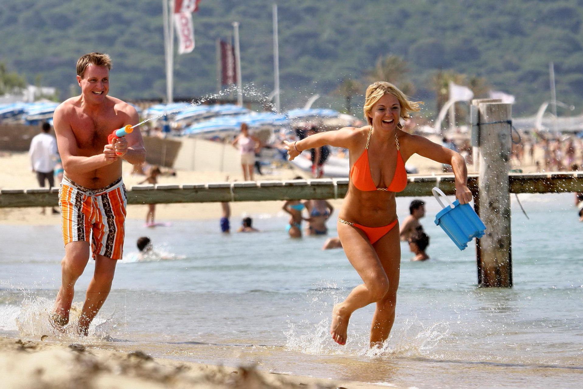 15P Busty Geri Halliwell showing pokies in skimpy orange bikini at Club 55 beach in 