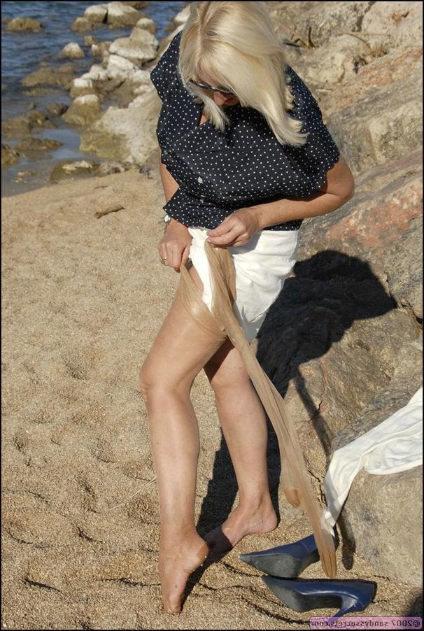 12P Seductive blonde lady shows off her wonderful long legs and stockings on the beach.