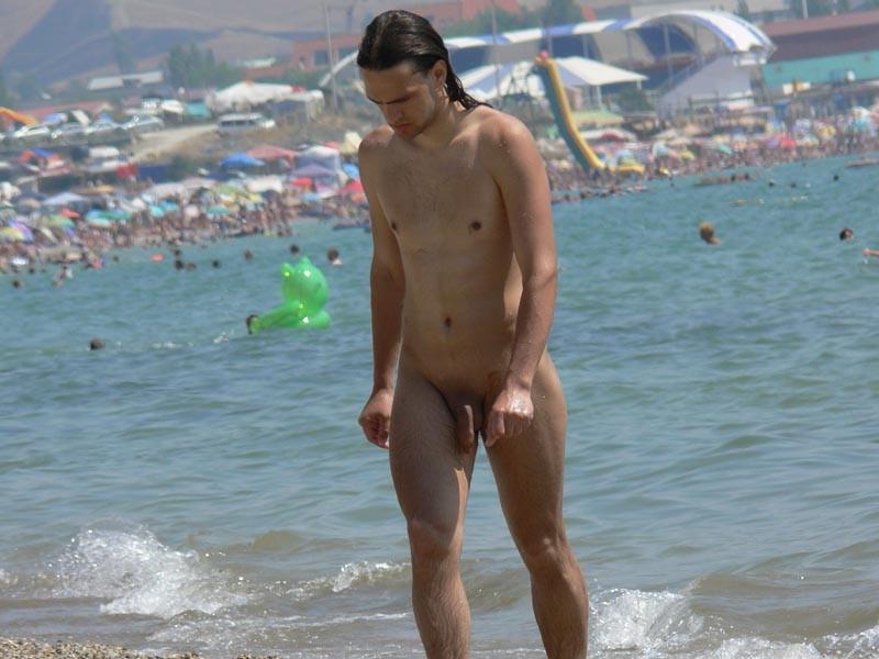 15P Brunette nudist kicks up some water at a nude beach