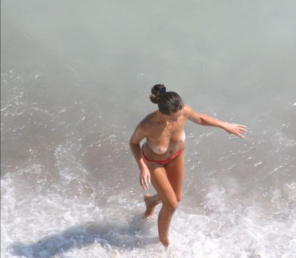 15P Blonde nudist kicks up some water at a nude beach