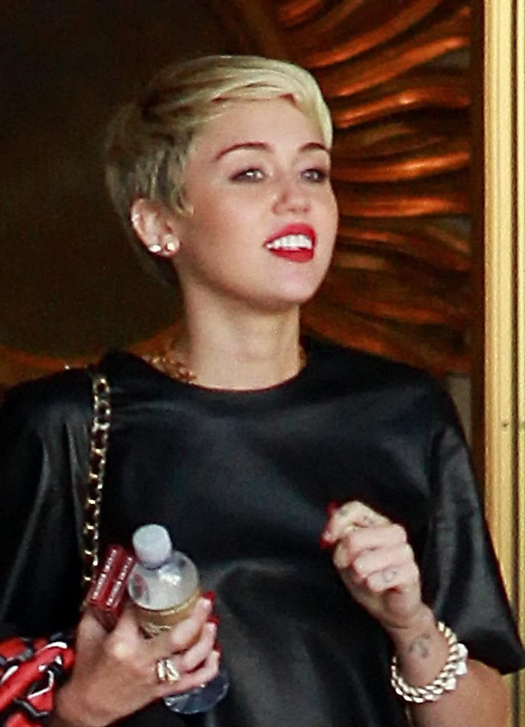 16P Miley Cyrus leggy wearing a denim shorts  a leather top out in Beverly Hills