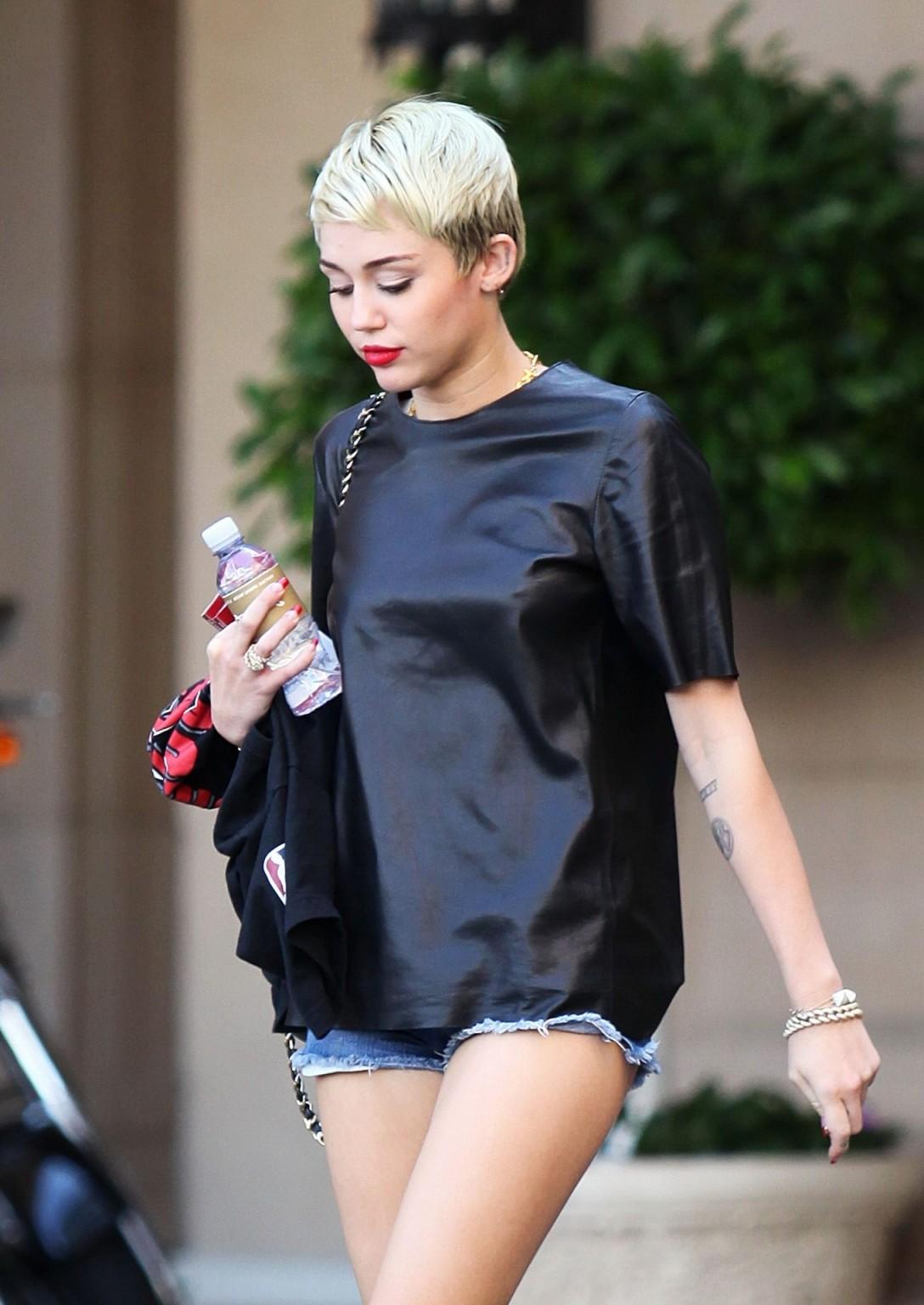 16P Miley Cyrus leggy wearing a denim shorts  a leather top out in Beverly Hills