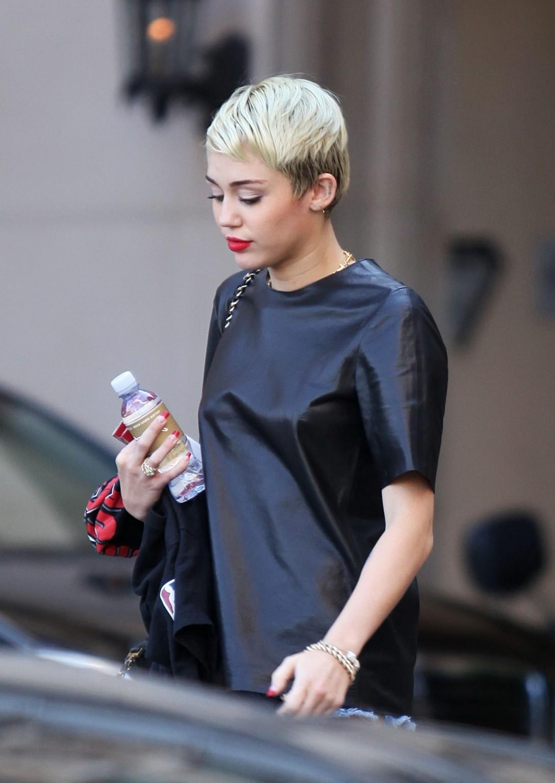 16P Miley Cyrus leggy wearing a denim shorts  a leather top out in Beverly Hills