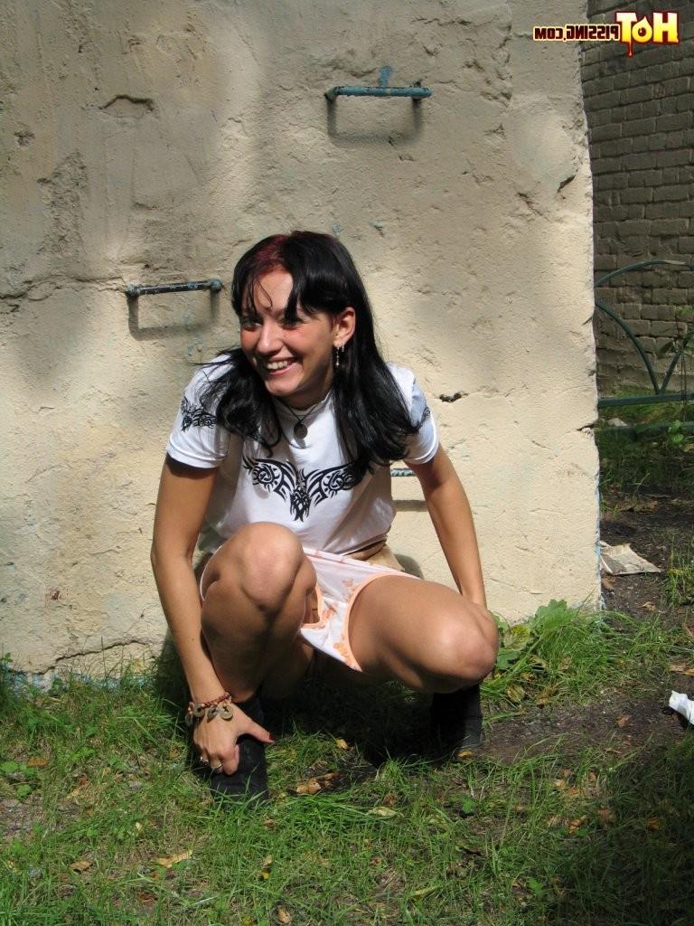 15P Blushing wench pulls down her panties to do a leak behind a building