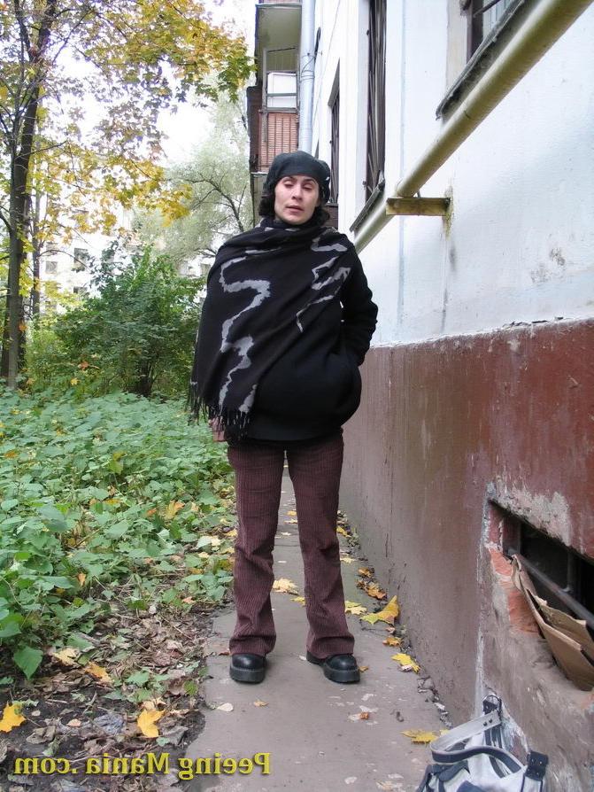 15P Stylishly dressed pretty woman does a leak behind a building in autumn