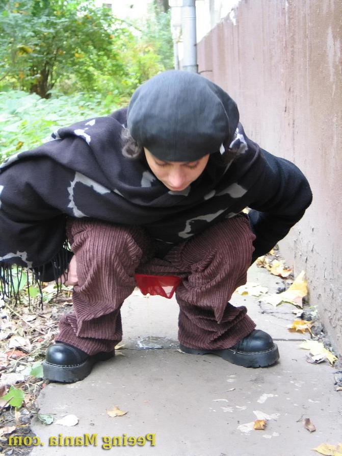 15P Stylishly dressed pretty woman does a leak behind a building in autumn
