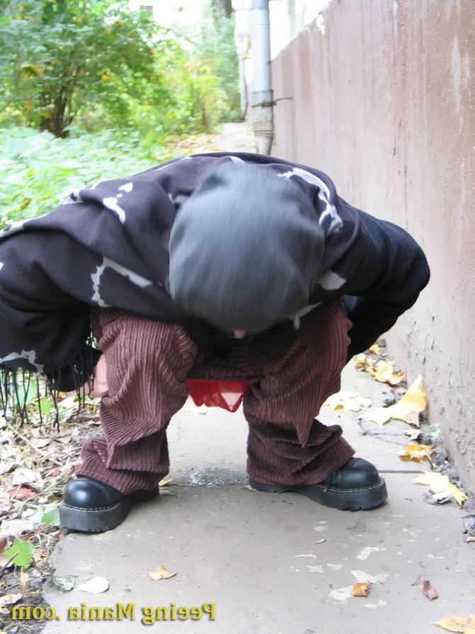 15P Stylishly dressed pretty woman does a leak behind a building in autumn