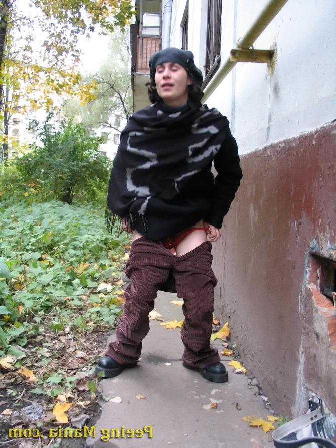 15P Stylishly dressed pretty woman does a leak behind a building in autumn