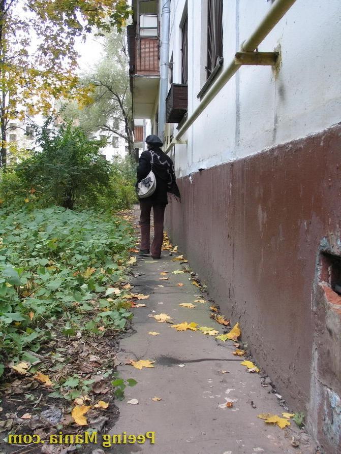 15P Stylishly dressed pretty woman does a leak behind a building in autumn