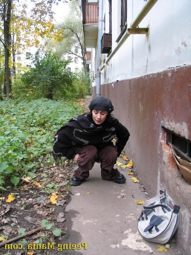 15P Stylishly dressed pretty woman does a leak behind a building in autumn