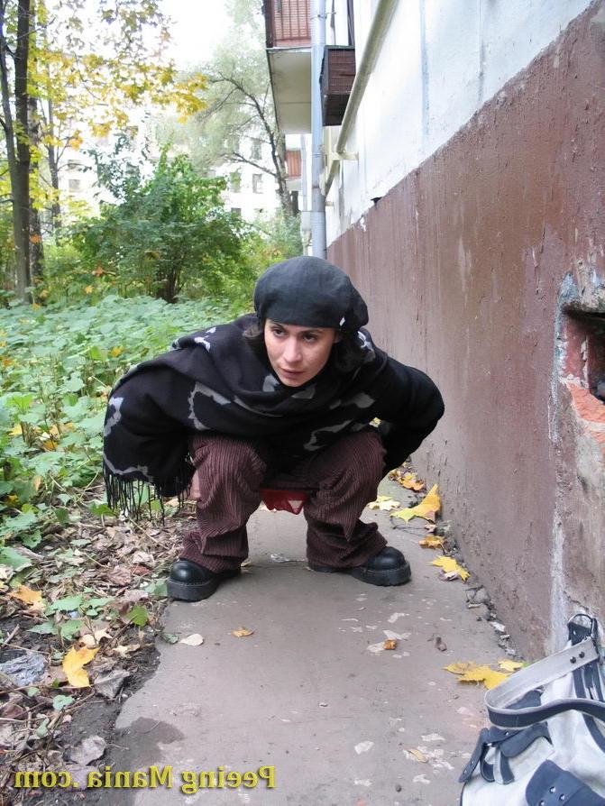 15P Stylishly dressed pretty woman does a leak behind a building in autumn