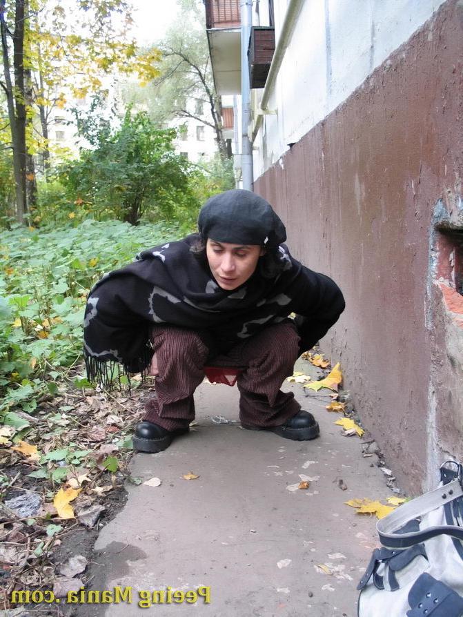 15P Stylishly dressed pretty woman does a leak behind a building in autumn
