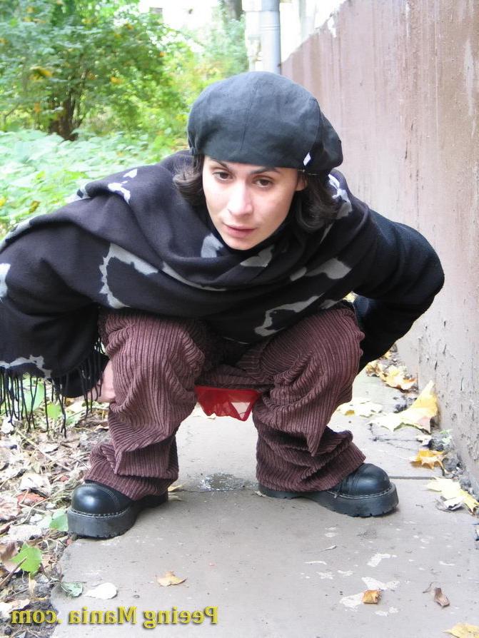 15P Stylishly dressed pretty woman does a leak behind a building in autumn