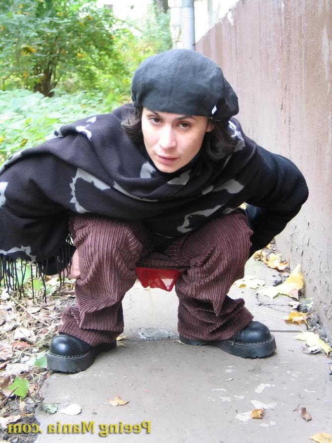 15P Stylishly dressed pretty woman does a leak behind a building in autumn