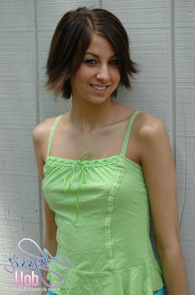 15P Alyssa strips out of her green and blue outfit by the wall