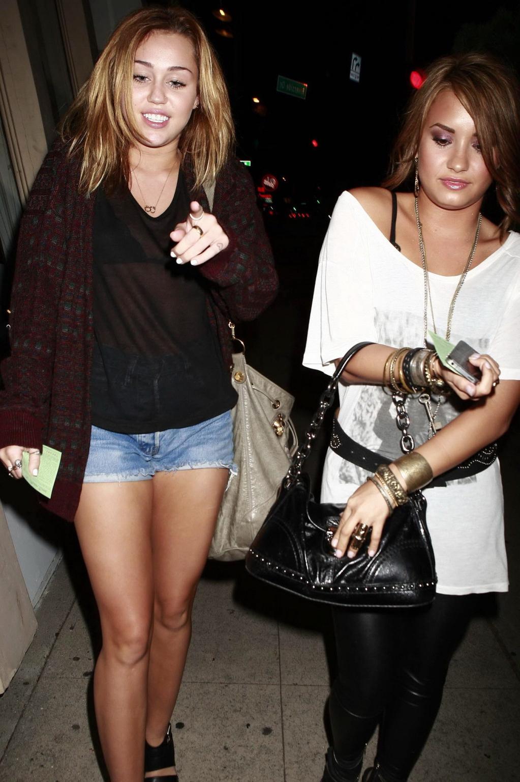16P Miley Cyrus wearing denim shorts  black bra under see-through top in LA