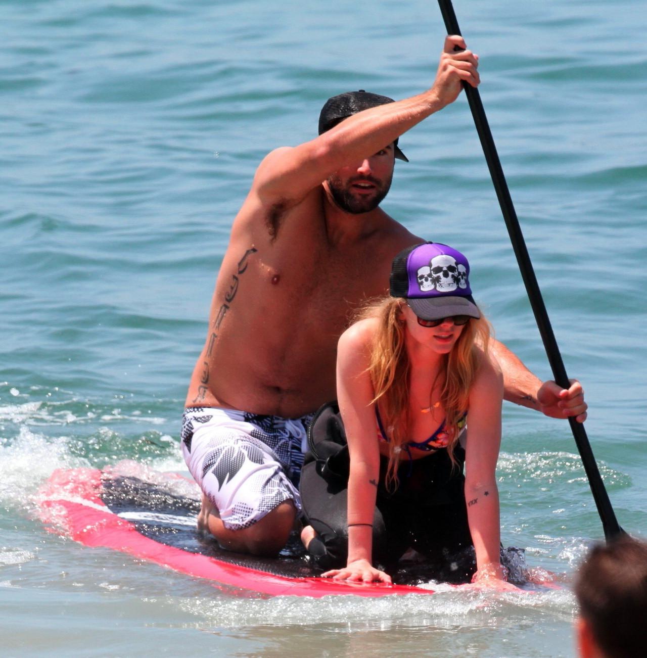 13P Avril Lavigne wearing a bikini top and a wetsuit on the beach in Malibu