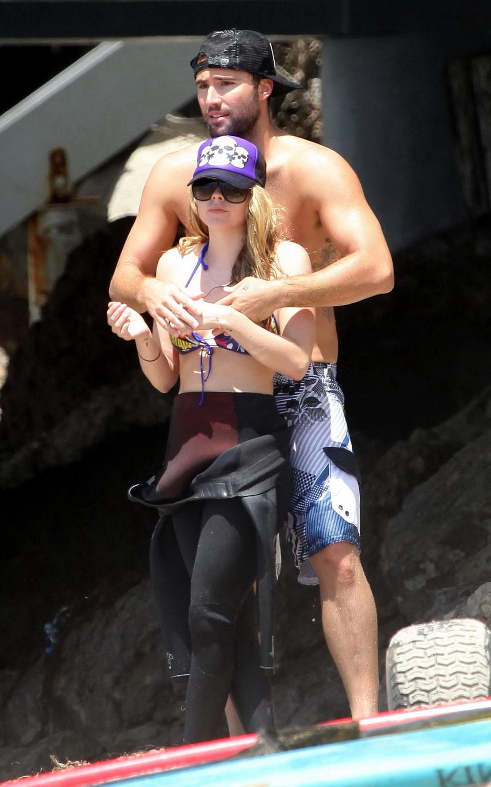 13P Avril Lavigne wearing a bikini top and a wetsuit on the beach in Malibu