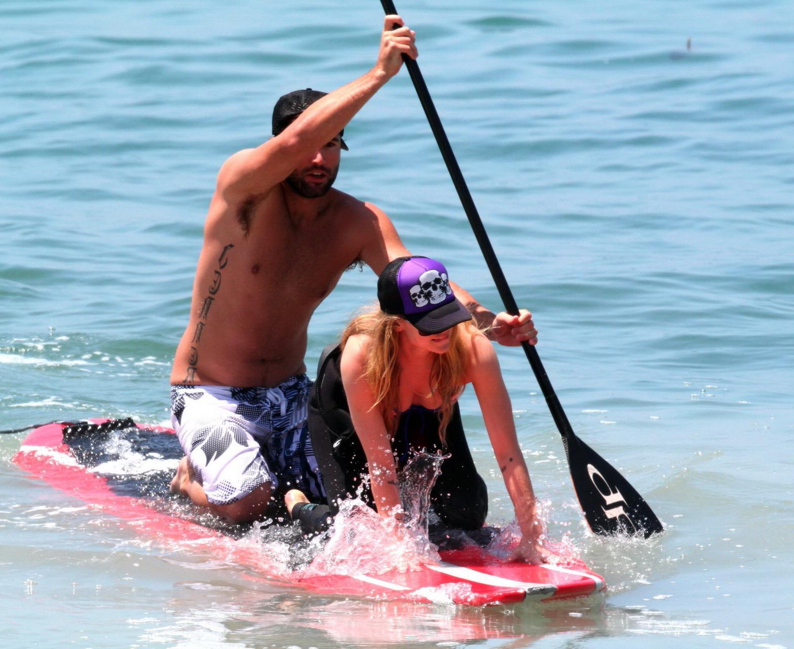 13P Avril Lavigne wearing a bikini top and a wetsuit on the beach in Malibu
