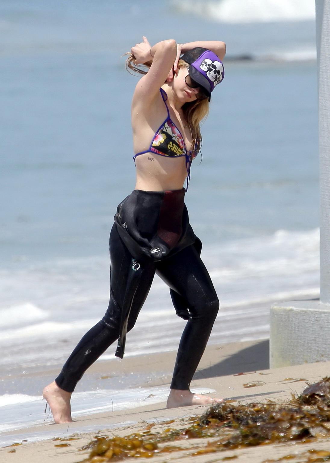 13P Avril Lavigne wearing a bikini top and a wetsuit on the beach in Malibu