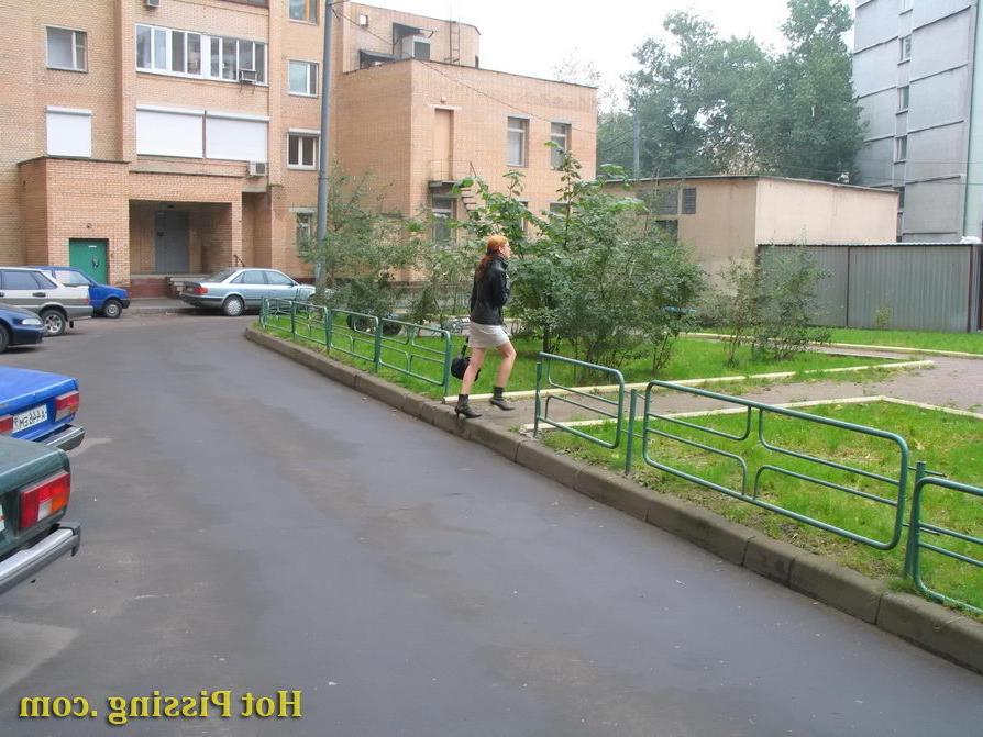 15P Hidden camera photos of a redhead girl having a pee behind a building