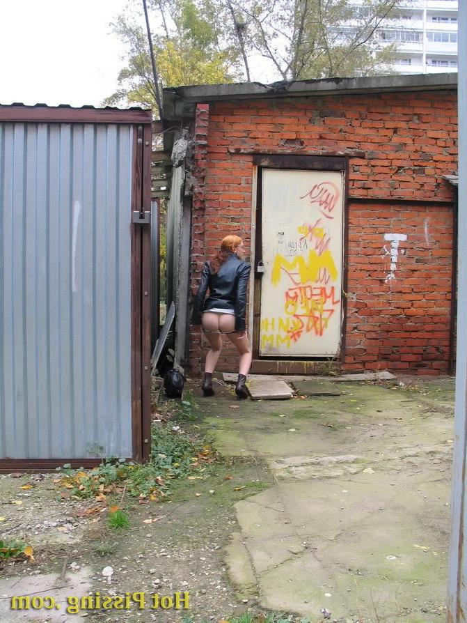 15P Hidden camera photos of a redhead girl having a pee behind a building