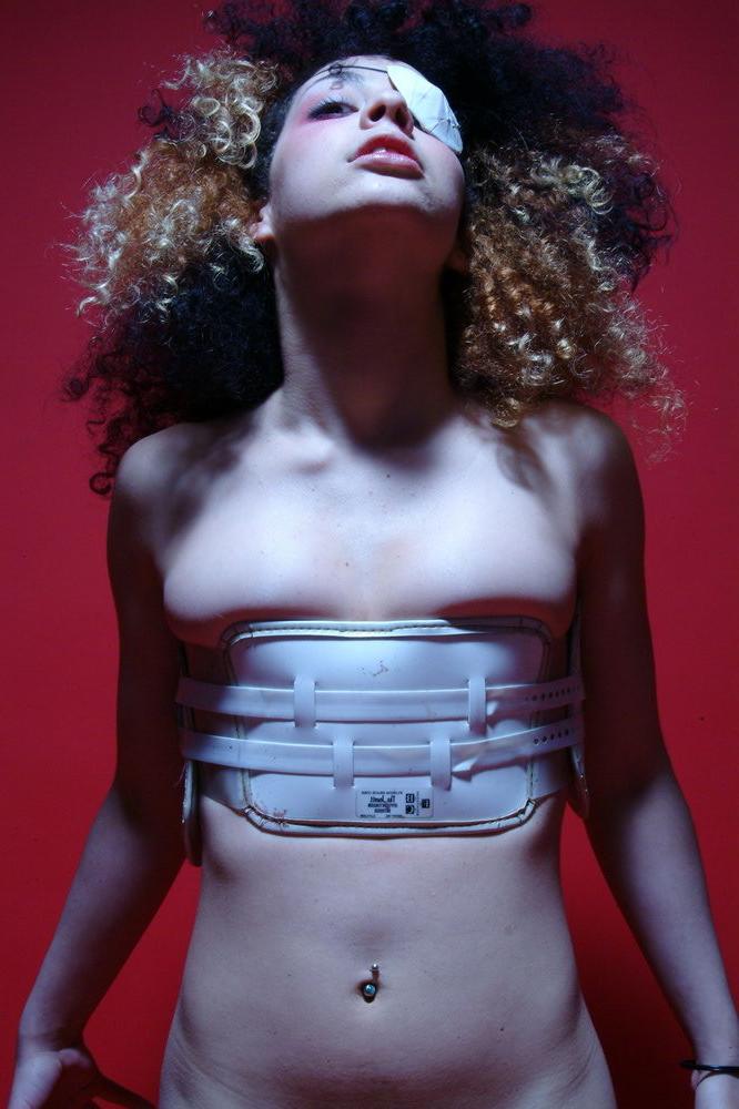 15P Gimp girl Kinky Zee posing in a back brace and eye patch