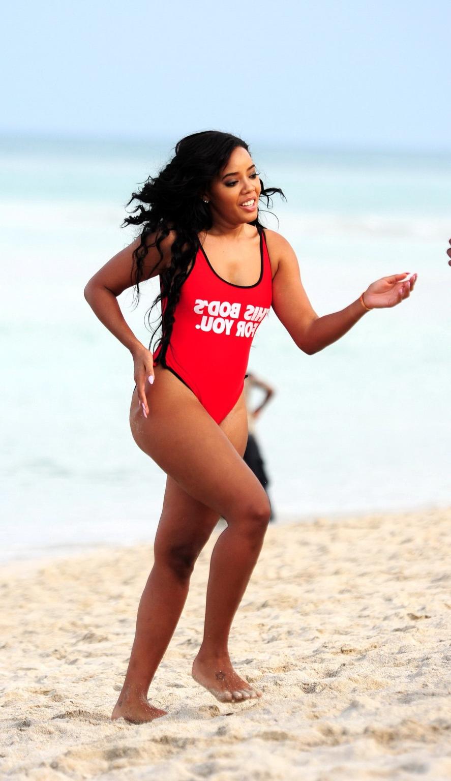 12P Angela Simmons in red swimsuit doing a bridge on a beach in Miami